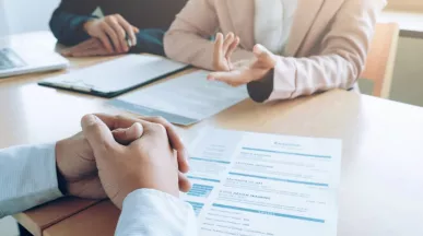 Entrevista de trabajo con revisión de un currículum vitae sobre la mesa, en un contexto de decisiones de contratación en empresas peruanas.