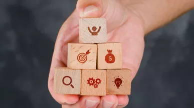 Mano sosteniendo bloques de madera en forma de pirámide con íconos que representan beneficios laborales peru