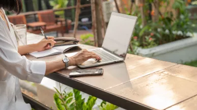 Mujer trabajando de forma remota desde una laptop en un espacio al aire libre.