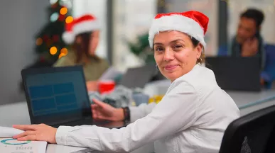 Una mujer feliz trabajando con un gorro de Navidad puesto.