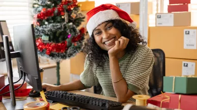 Una mujer con gorro navideño sonríe mientras trabaja.