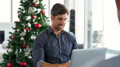 Hombre trabajando con un árbol de Navidad al fondo.