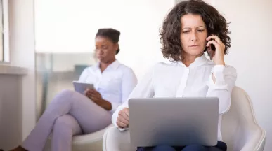 Mujer atiende una llamada con una computadora en su regazo, en una escena que ilustra los desafíos de la desconexión digital.
