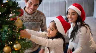 Niña decora el árbol de Navidad de su casa junto a su familia.