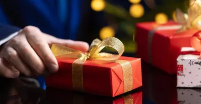 hombre sosteniendo un regalo navideño corporativo en su mano