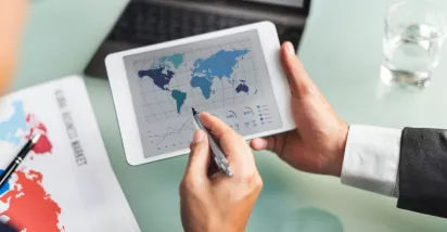 Profesional analizando datos del mercado global en una tablet durante la jornada laboral