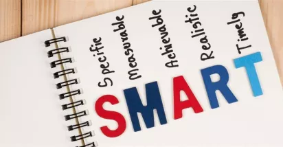 Cuaderno con la palabra SMART y sus componentes, representando el método para definir objetivos SMART claros, medibles y alineados en las empresas.