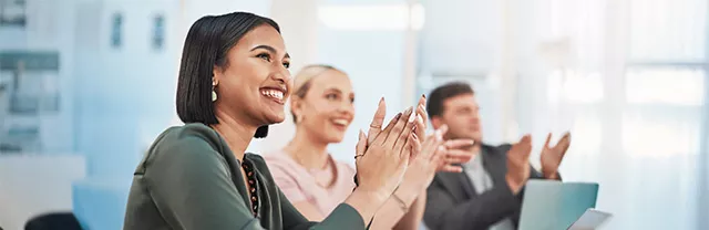Foto muestra a tres personas celebrando un logro en el trabajo.