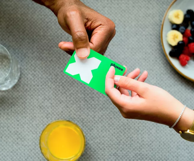 Tarjeta Pluxee Navidad siendo utilizada durante una comida, destacando beneficios corporativos para colaboradores en celebraciones de fin de año.