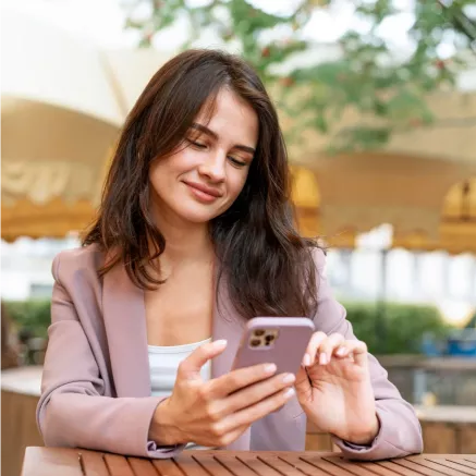 Chica mirando su celular en su manos mientras sonríe
