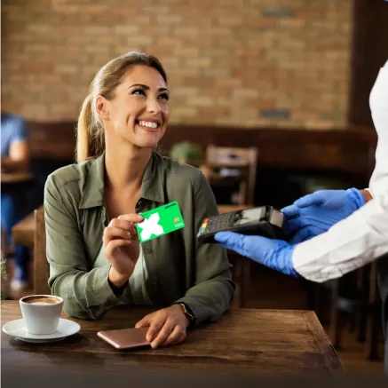 Chica pagando con su Tarjeta Pluxee en un POS mientras sonrie