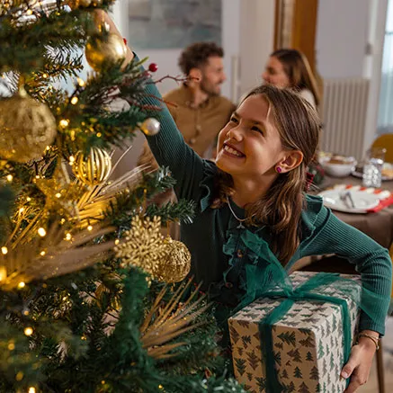 Niña ayuda a arreglar el árbol de Navidad