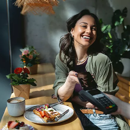 Mujer paga su almuerzo con la tarjeta virtual Pluxee.